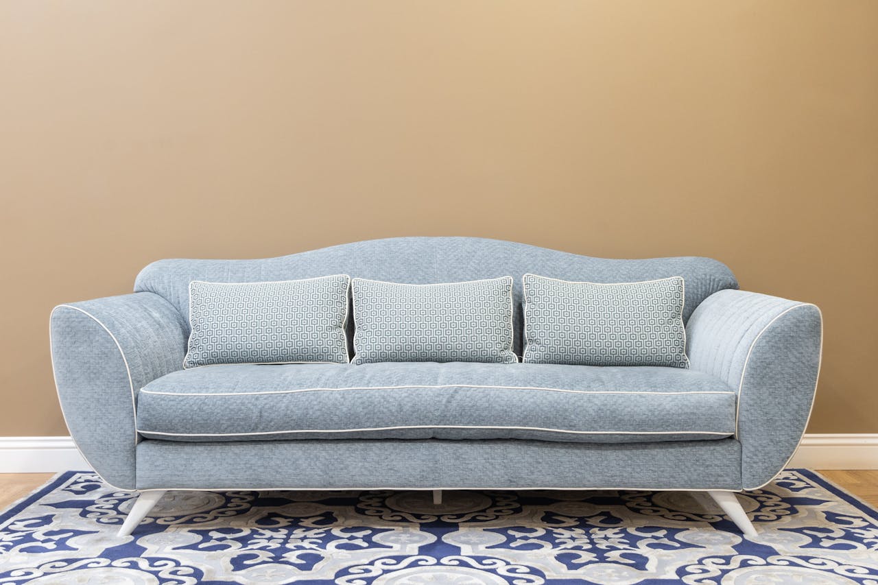hero-img-01 Stylish blue sofa with cushions on patterned carpet, perfect for a modern, cozy living space.