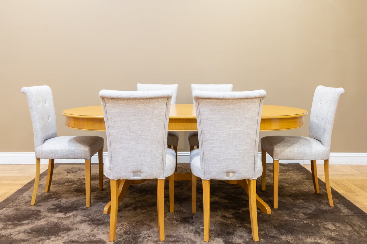 about-01 Sophisticated dining area showcasing a wooden table with beige upholstered chairs on a carpet.